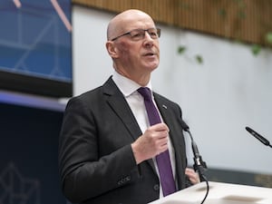 John Swinney at a podium making a speech