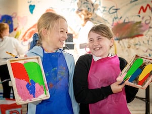 Two young girls show off their paintings