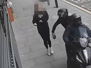 CCTV footage of two men on a scooter snatching a woman's mobile phone.