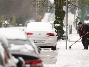 A man clears snow from the pavement in Ballylynan in County Laois, Ireland