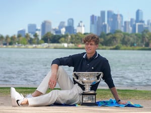 Jannik Sinner poses with Norman Brookes Challenge Cup in front of the Melbourne skyline