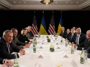 A number of men sitting around a long table