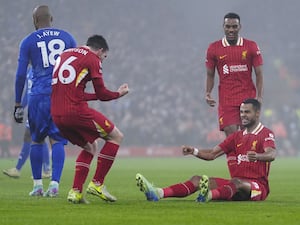 Cody Gakpo, sitting on the pitch, celebrates after scoring Liverpool’s first goal against Leicester