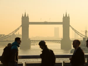 Commuters with Tower Bridge, in central London, in background as they cross London Bridge