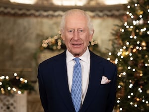 The King smiles before a Christmas tree during the recording of his Christmas message at the Fitzrovia Chapel in central London