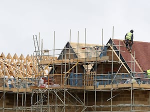 Builders standing on scaffolding construct a house