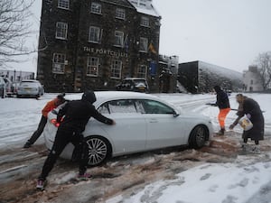 People help a driver in the snow in Stirling, Scotland, during Storm Bert