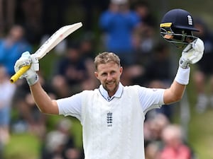 Joe Root raises his bat and helmet to celebrate his century