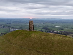 People watch the sun rise on Glastonbury Tor over the Somerset levels