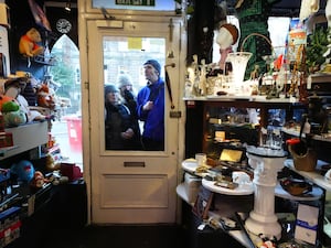 Shoppers seen through the door of a shop with laden shelves