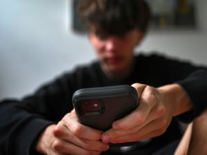 A teenager uses his mobile phone to access social media,