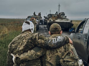 A Ukrainian soldier helps a wounded comrade