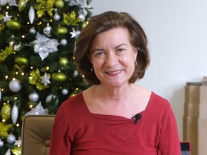 First Minister Eluned Morgan, wearing red, smiles at the camera in front of a Christmas tree