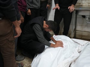 A Palestinian man mourns over bodies of a victim following Israeli bombardments, at the morgue of Al-Aqsa Martyrs Hospital in Deir al-Balah, Gaza Strip