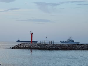 The Italian navy ship (right) with 49 migrants on board approaches the port of Shengjin in north-western Albania