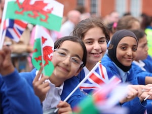 Schoolchildren wave flags outside the Senedd ahead of the King's arrival to mark its 25th anniversary in July