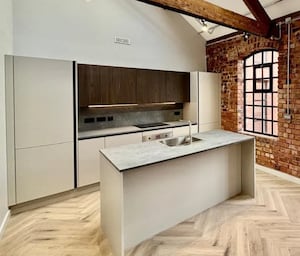 The kitchen features an exposed brick wall design and exposed roof trusses 