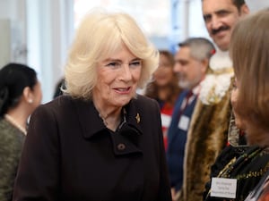 Queen Camilla smiling as she talks to guests at a domestic abuse centre