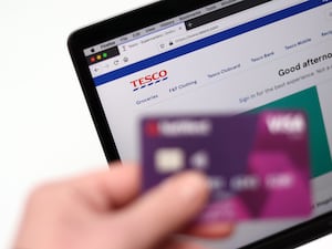 The Tesco website is pictured on a laptop with a bank card.