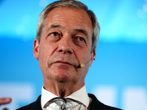 Nigel Farage wearing a headset with a small microphone attached to it at a Reform UK conference