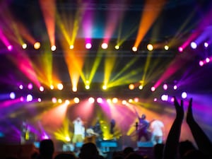 Abstract image with blurry musicians on stage with colourful lights during the concert