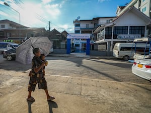 A woman carries a baby as she walks by the Nana Backpack hostel in Vang Vieng, Laos