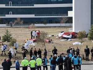 Debris on the ground after helicopter crash, with people looking on