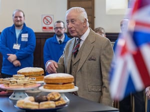 The King admires cakes on a table, with British flags to the right of the picture