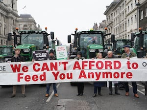 Farmers with tractors and a banner that says 'we can't afford to feed you anymore'