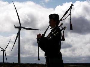 Silhouette of bagpiper performing near some wind turbines