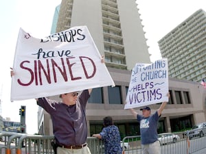 Dave West, left, and his brother Larry West, both of Fort Worth, Texas, demonstrate outside the meeting