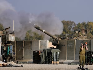 An Israeli soldier covers his ears as an artillery gunner fires into the Gaza Strip