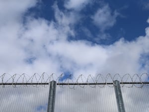 A prison fence with blue sky behind