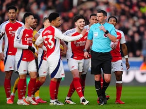 Arsenal players surround referee Michael Oliver, front right