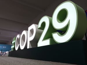 An attendee walks near a sign for the COP29 UN Climate Summit