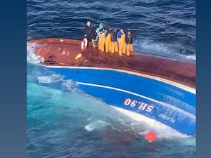 Crew standing on capsized hull