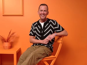 Scott Mills sitting on a chair in an orange room