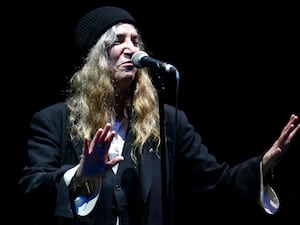 Patti Smith wearing a hat and performing in 2014