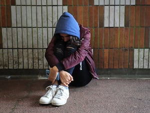 Girl wearing a hooded top crouched over