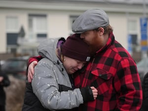 People gather at a makeshift memorial near the scene of a shooting on the outskirts of Orebro, Sweden