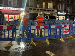 Workmen cordon off part of a London road to work on a burst water pipe