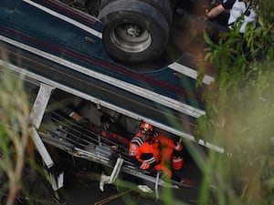 A firefighter works inside the bus that fell from a bridge