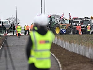 A person in hi-vis looks at a line of tractors during a protest